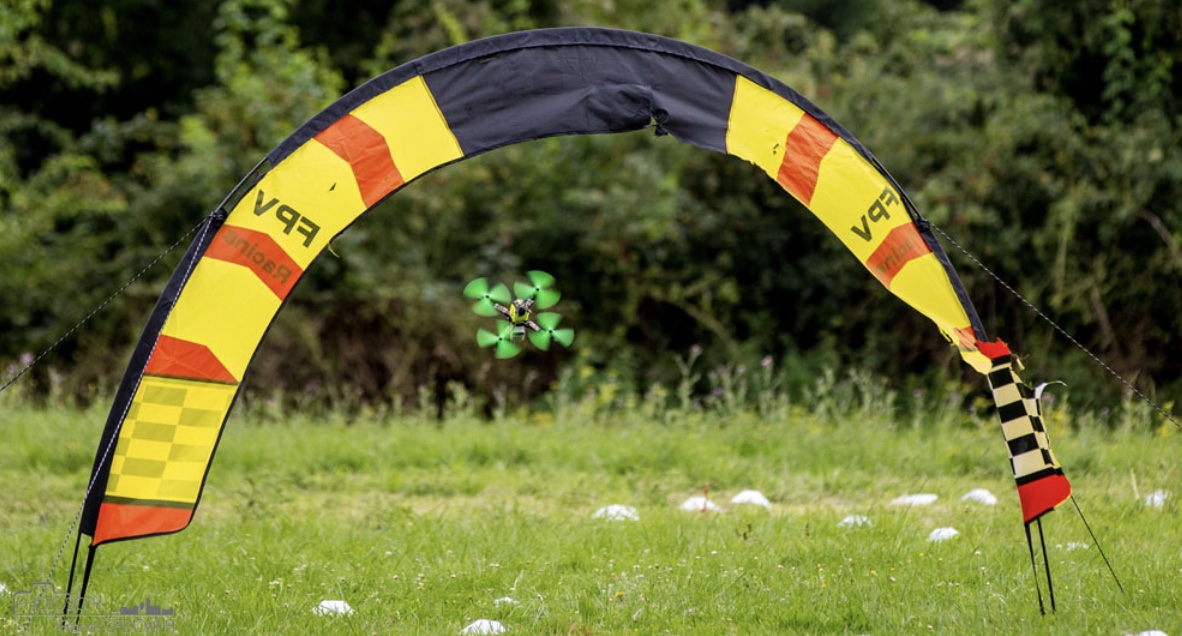 Drone racer FPV vert franchissant une porte de course